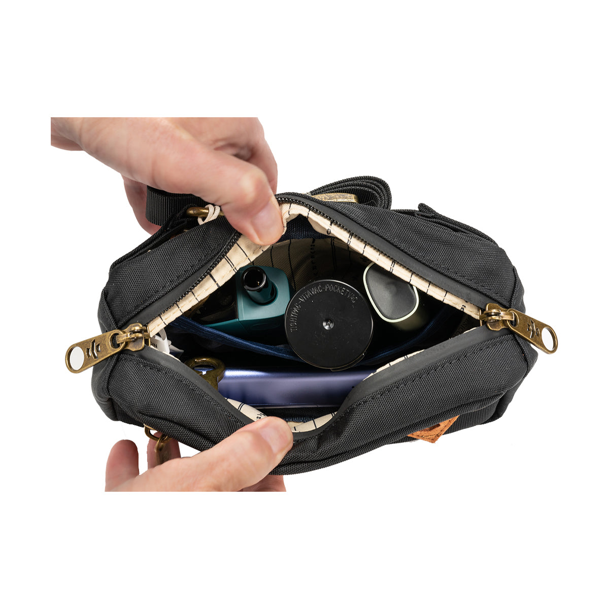 revelry the companion smell proof crossbody bag black with vaporizers in hand view.jpg